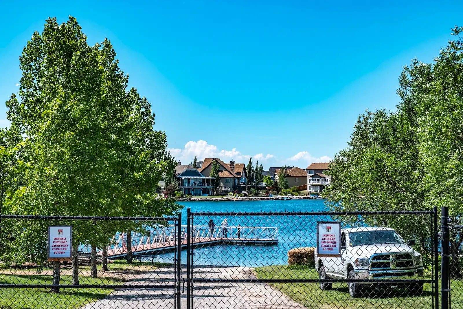 Auburn Bay lake and dock seen through the access gate, with homes across the water
