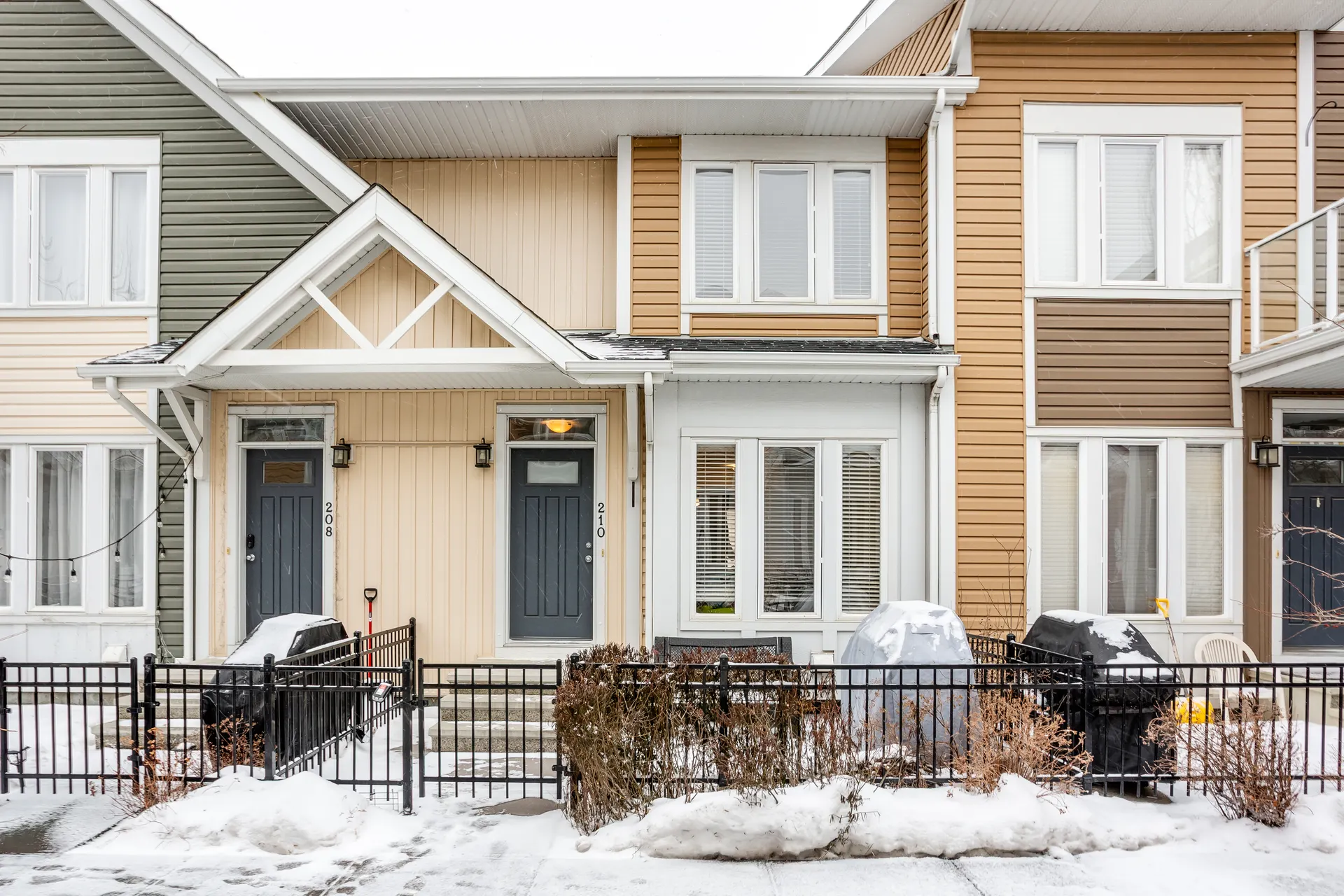 Auburn Bay townhomes with sage, cream and ochre siding and fenced front yards in winter