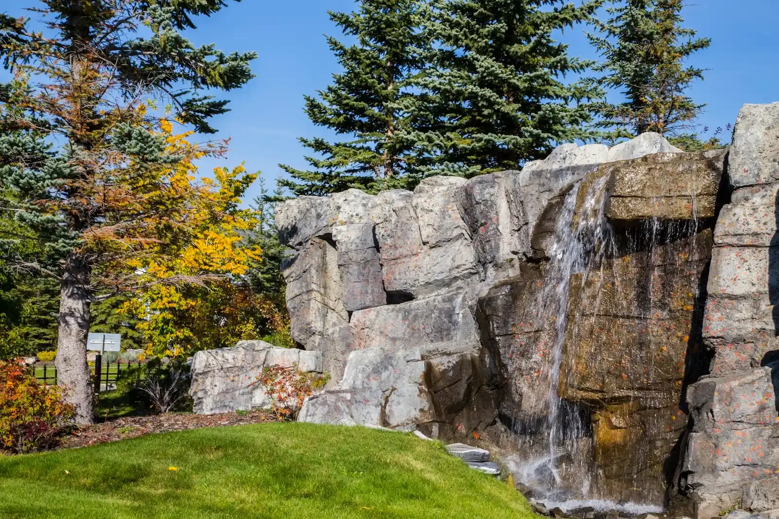 Discovery Ridge stone waterfall surrounded by evergreen trees and autumn foliage