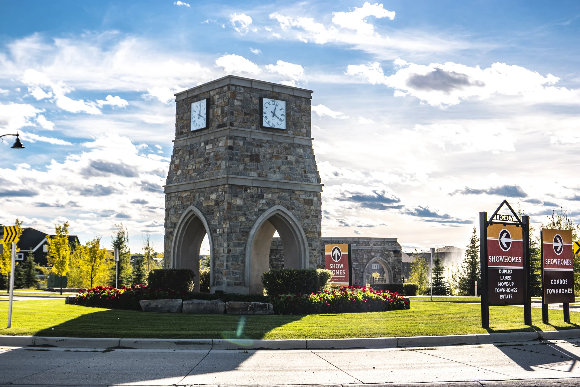 Photograph of Legacy's stone clock tower, arched base, flower beds and clipped hedges